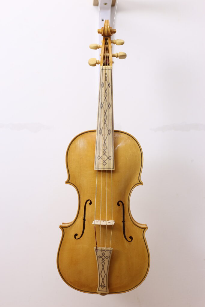 Vooraanzicht van een viool met versierde toets en staartstuk, snaren en f-gaten zichtbaar