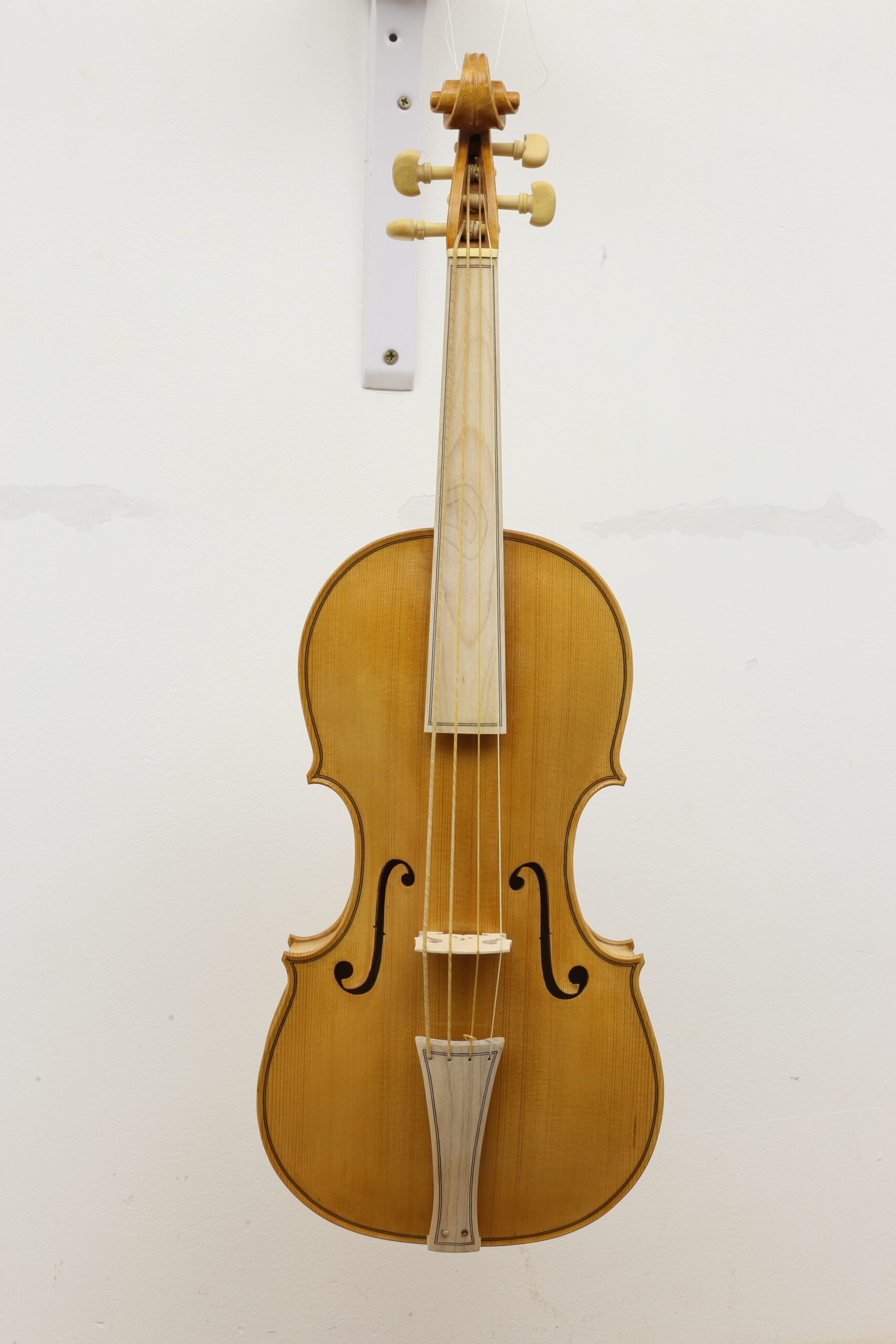 Volledig vooraanzicht van een viool hangend aan de muur met snaren, brug en f-gaten zichtbaar